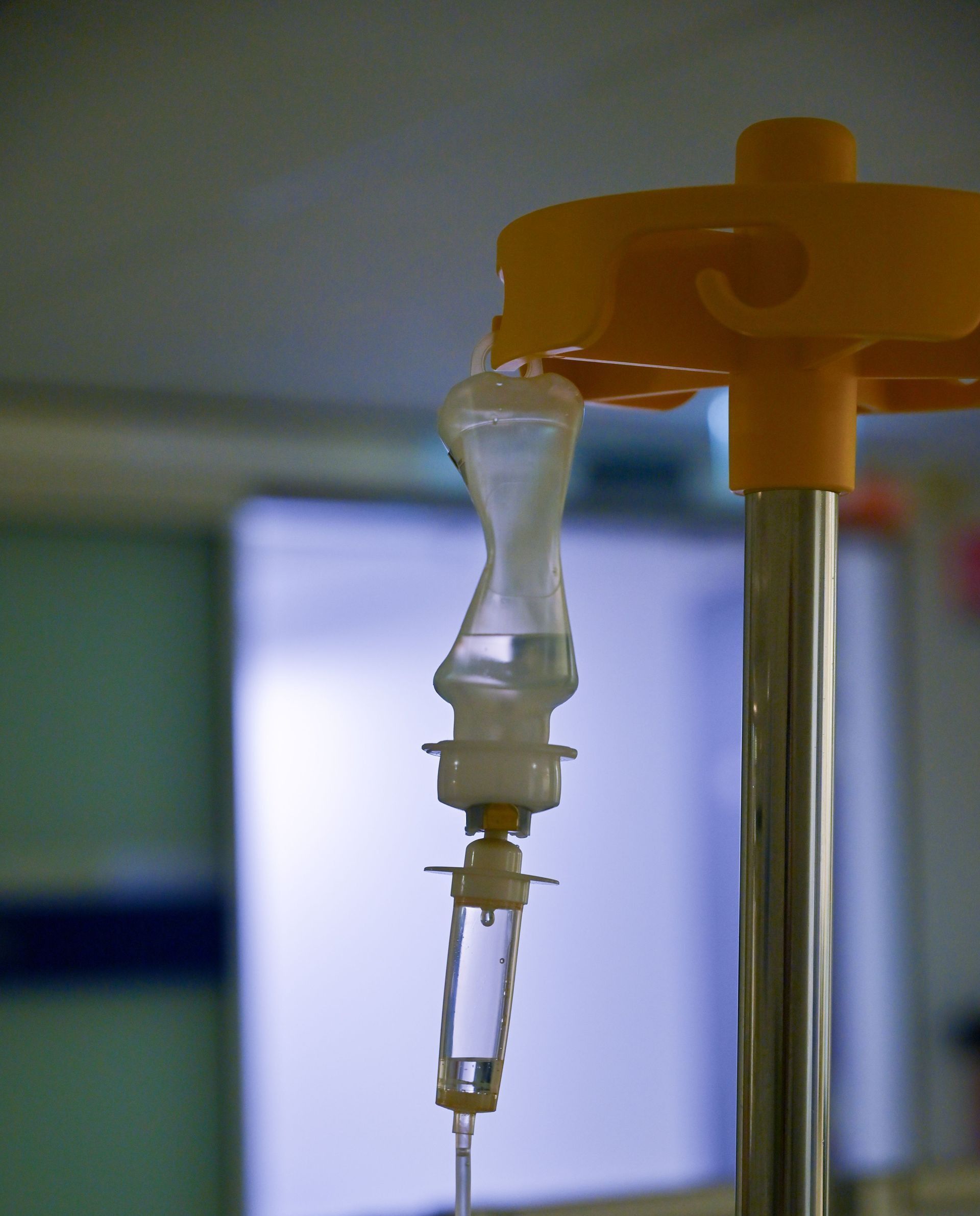 Close-up image of an intravenous drip with blurred hospital background, highlighting medical equipment in use.