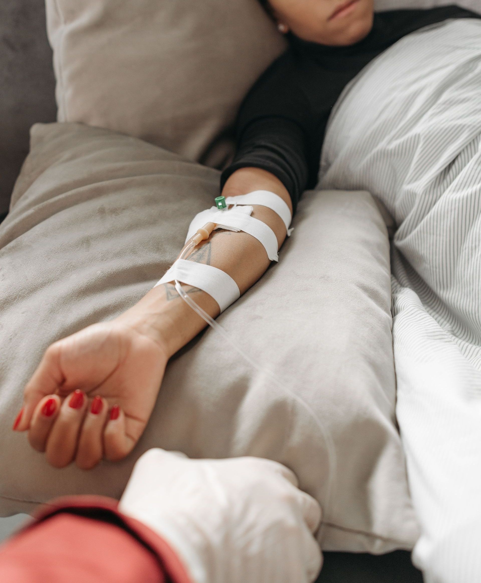 Woman lying in bed with medical tubes, depicting recovery or illness in an indoor setting.