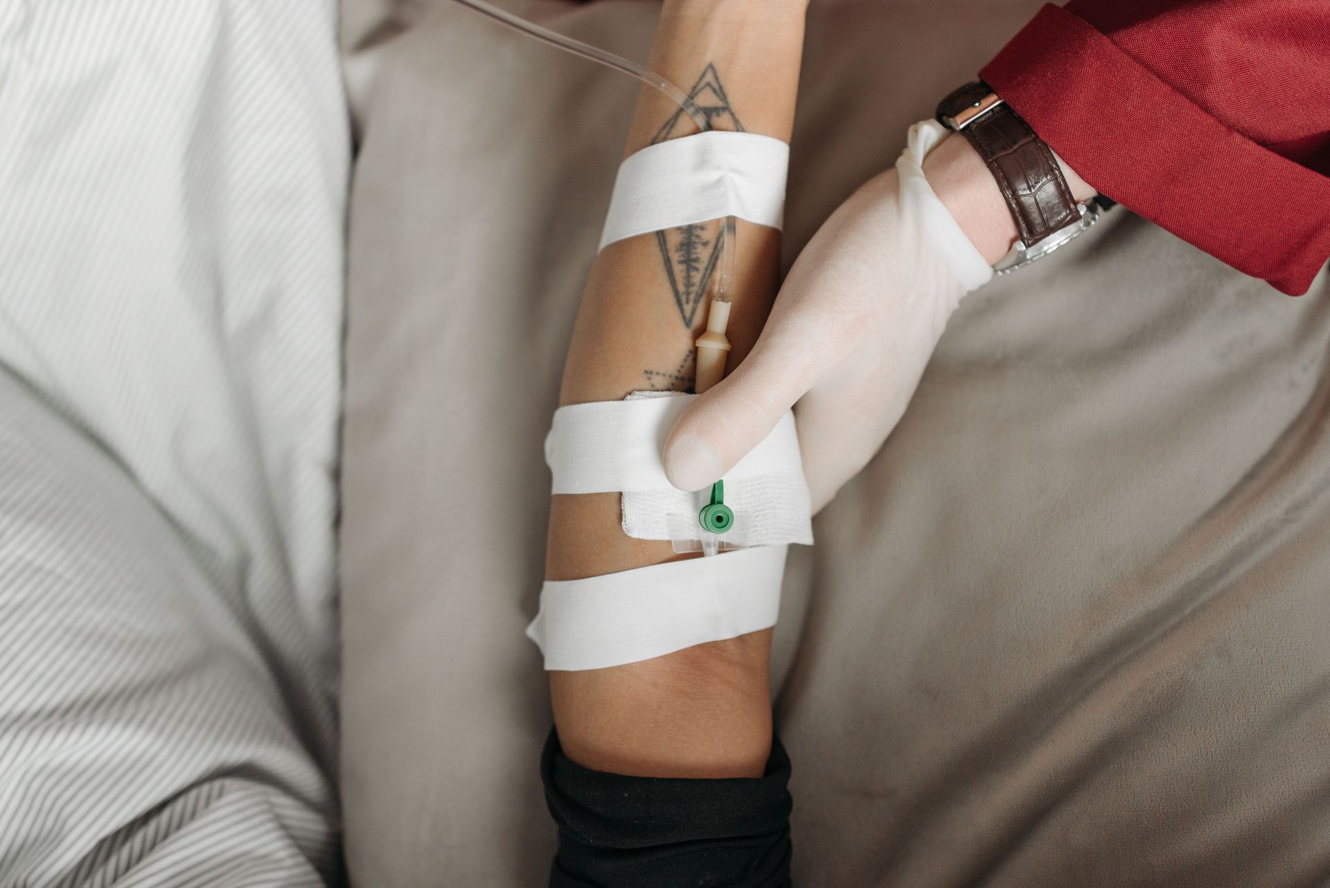Close-up of a healthcare worker administering an IV to a patient's arm, focusing on the medical procedure.